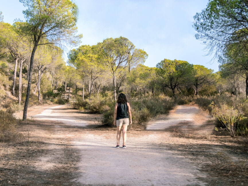 Woman standing in front of two paths, deciding which one to take.